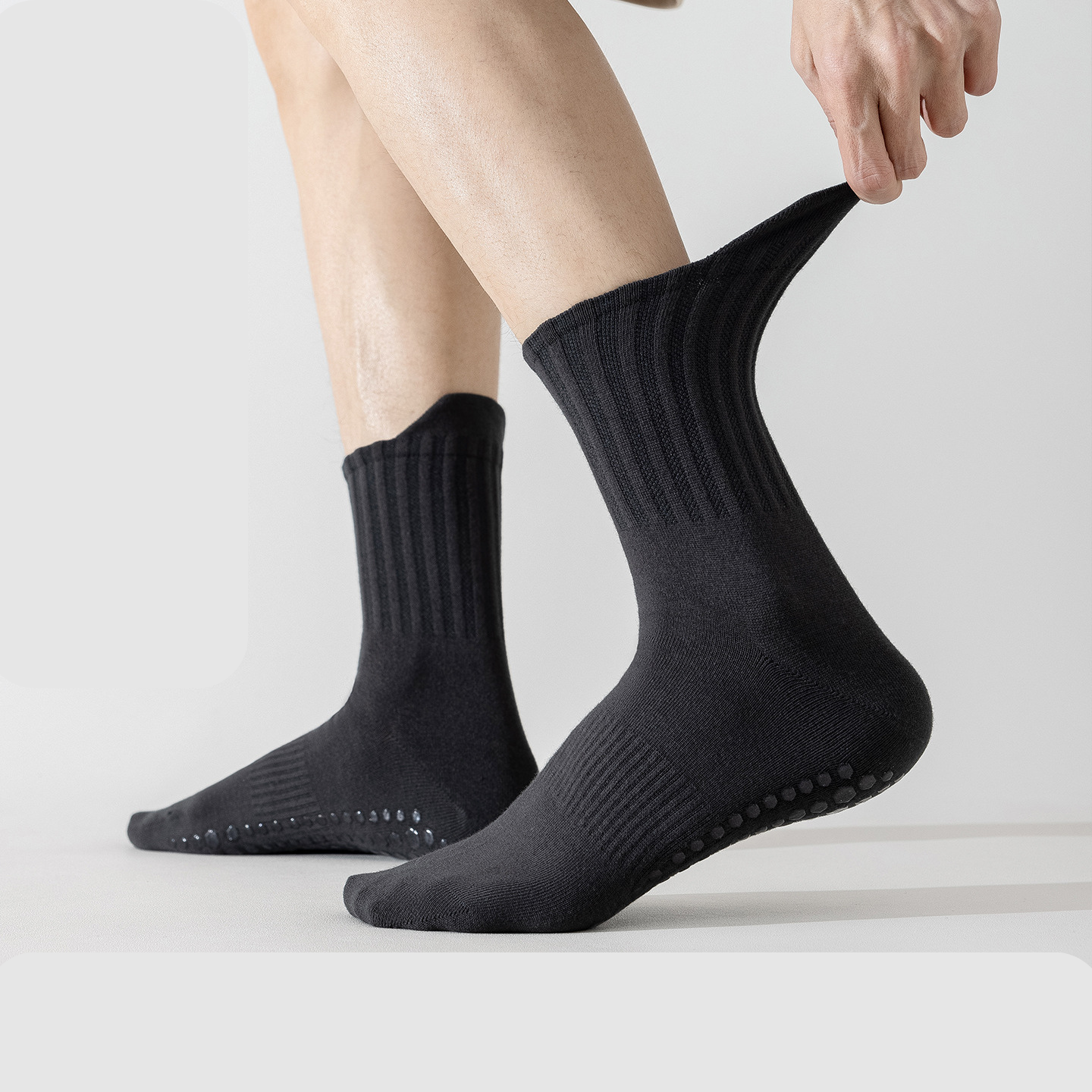 Person wearing black socks with non-slip sole on a light gray background